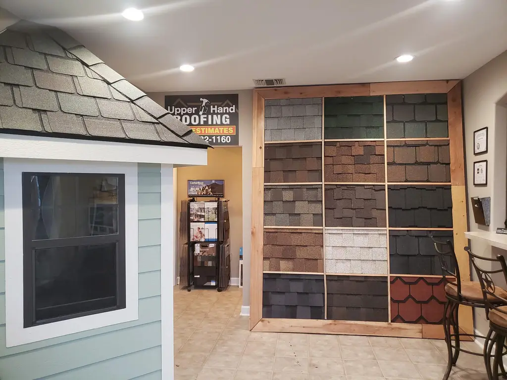 Upper Hand Roofing showroom wall lined with real shingle color and style samples in a cedar frame