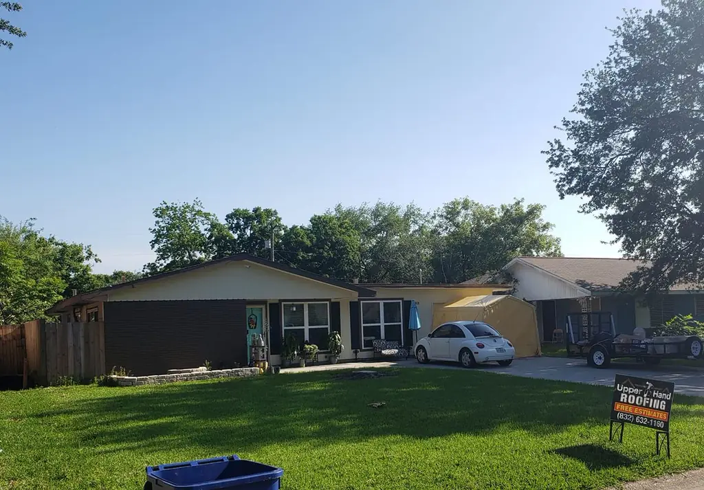 A residential job site with an Upper Hand yard sign and a work canopy set up in the driveway.